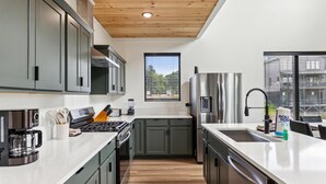 Una cocina moderna con gabinetes grises, electrodomésticos de acero inoxidable y un ventanal que proporciona luz natural.
