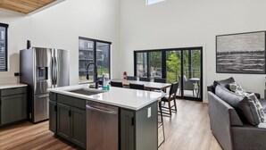 Una cocina moderna con una isla central, electrodomésticos de acero inoxidable y amplios ventanales con vistas a zonas verdes.