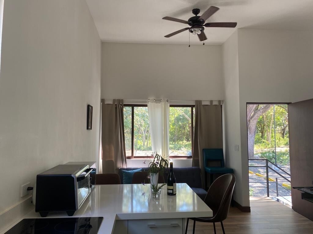 A modern living room with a dining table, sofa, and a ceiling fan.