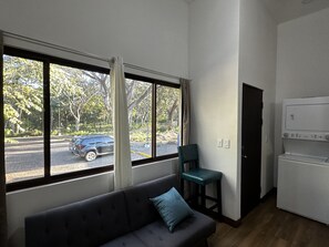 A room with a large window, a sofa, a chair, and a washing machine. - Peaceful Apartment in Tamarindo, 50m to the Beach (Tamarindo)