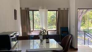 Ett modernt kök med en köksö i mitten, en takfläkt och stora fönster med gardiner.