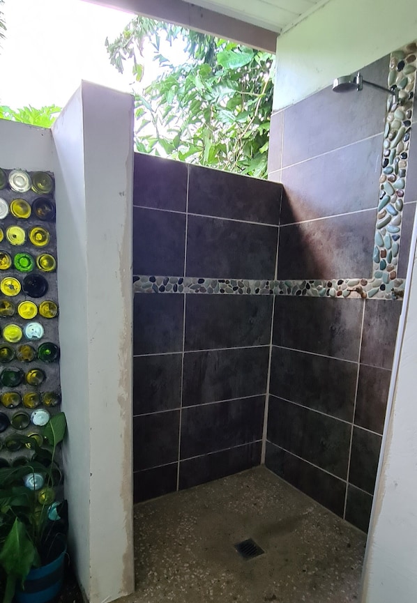 Un espacio de ducha pequeño y cerrado, con azulejos oscuros y un borde decorativo.
