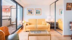 A living room with a sofa, a glass coffee table, and a view of the outside.