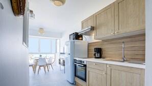 Una cocina moderna con armarios de madera, horno empotrado, refrigerador y cafetera.