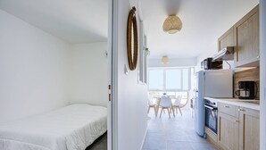 Una habitación compacta y moderna con cama, kitchenette y comedor con vistas.