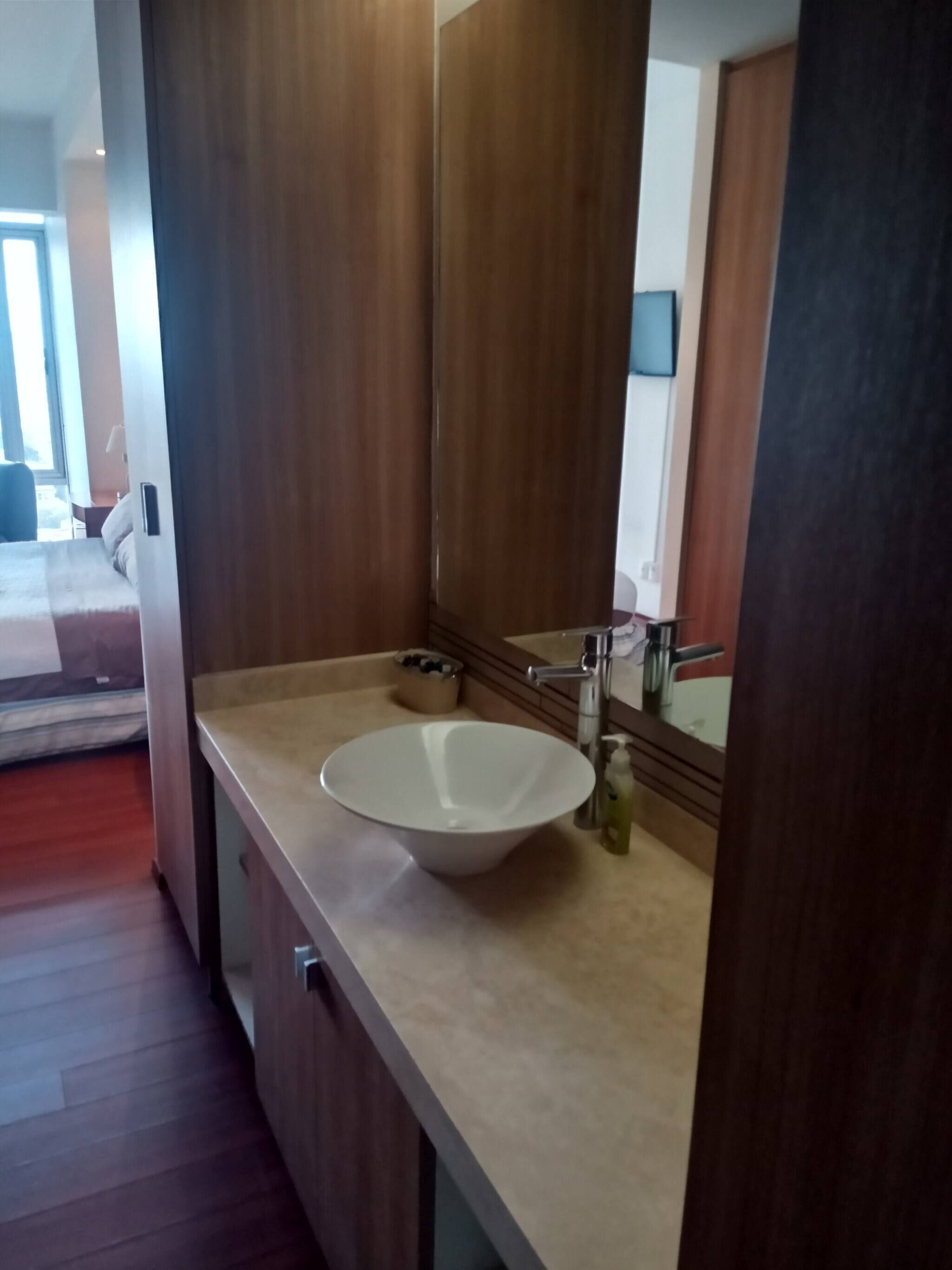 Une salle de bain moderne avec un grand miroir, un lavabo blanc et un meuble-lavabo en bois.