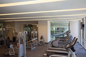 A gym with treadmills, weight machines, and a glass wall offering a view of the city.