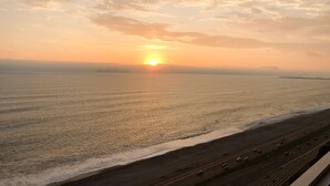 A sunset over a coastal highway with a beach and ocean. - Vista al mar a 15 min del aeropuerto (La Perla)