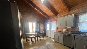 Una cucina con mobili in legno, un tavolo da pranzo con sedie e un frigorifero.