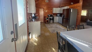 Una cucina compatta con isola centrale, elettrodomestici integrati e un'area pranzo con tavolo e sedie.