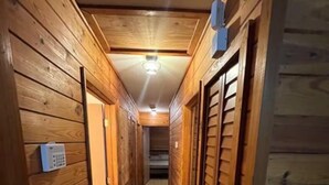 Un corridoio in legno con porte, una luce a soffitto e un termostato sulla parete.