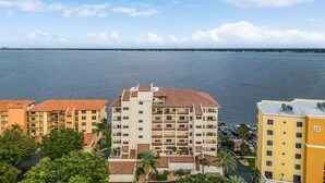 A coastal hotel with multiple floors, balconies, and a view of the sea. - RIVERFRONT VIEW, Stunning Sunrises, Community Pool - Condo Waterfront Sunrise - Roelens (Cape Coral)