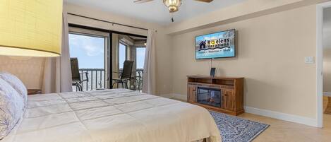 A bedroom with a bed, a ceiling fan, a TV, and a fireplace.