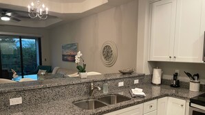 Una cocina moderna con encimeras de granito, electrodomésticos de acero inoxidable y armarios blancos.