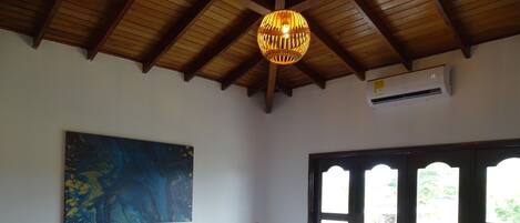 Une chambre d’hôtel avec deux lits, une grande peinture abstraite, un plafond en bois et une fenêtre donnant sur un beau paysage.