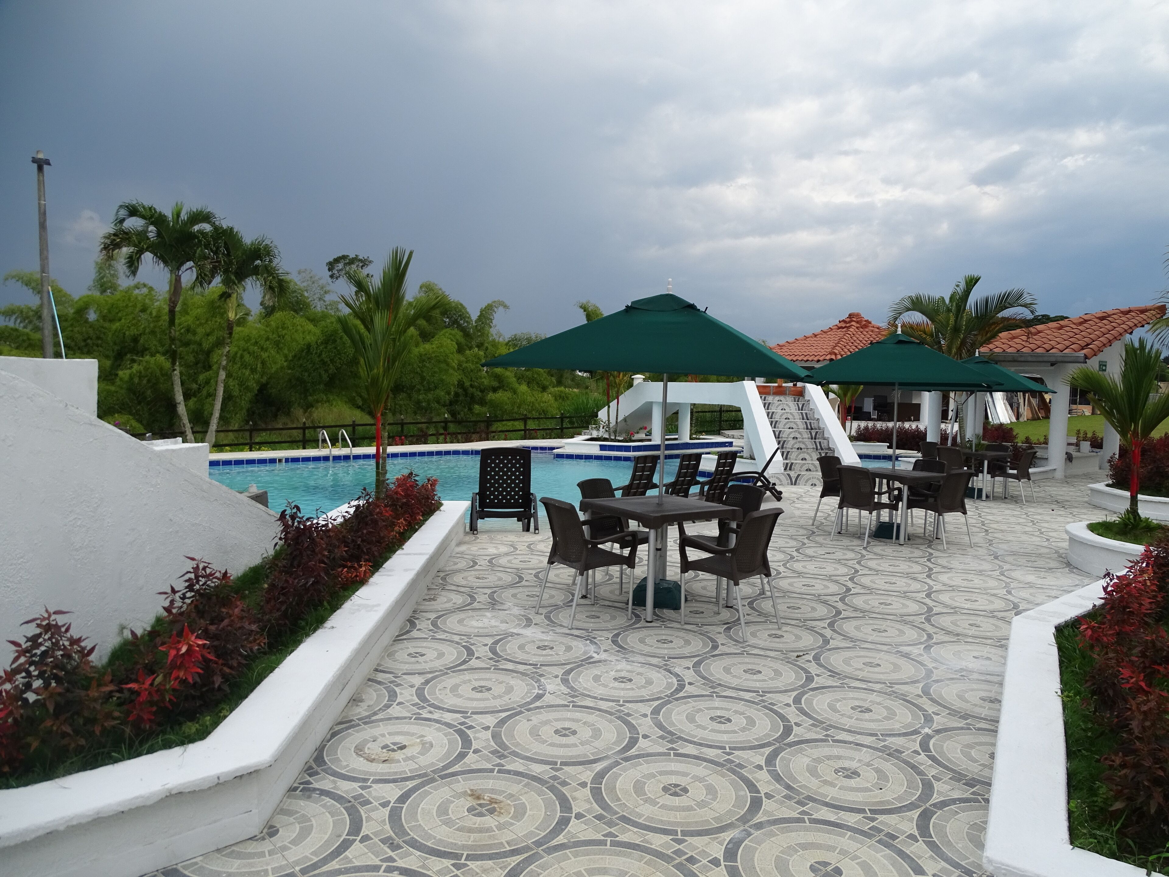 A poolside area with a tiled floor, outdoor seating, and a pool.