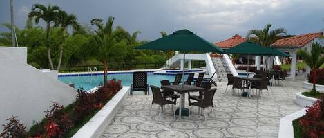 A poolside area with a tiled floor, outdoor seating, and a pool.