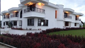 A multi-story white building with balconies, large windows, and a well-maintained garden. - Hotel Palmas De Alcalá (Alcalá)