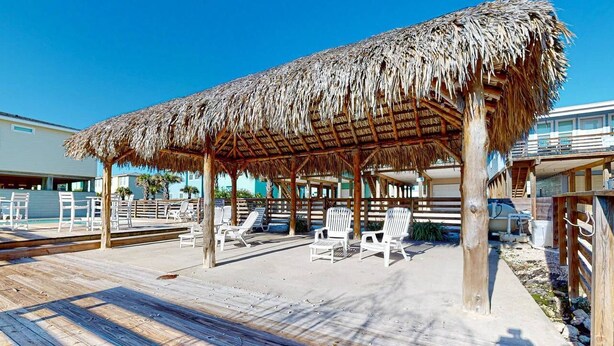 A beachside cabana with a thatched roof, wooden deck, and white lounge chairs. - OV17 Shared Pool, Pet Friendly, Golf Cart Access, Ping Pong Table (Port Aransas)