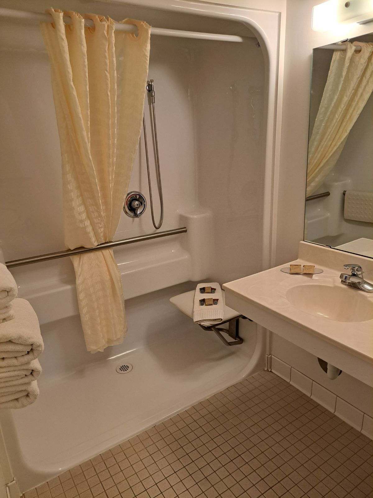 Un baño moderno con bañera, ducha, tocador con lavamanos y espejo.