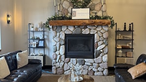 Una sala de estar acogedora con chimenea de piedra, una señal de cruce y un adorno navideño.