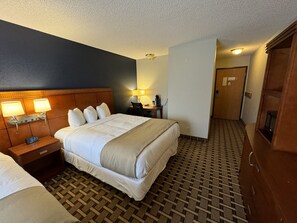A hotel room with a large bed, bedside lamps, a desk with a chair, and a wardrobe. - Crossroads Hotel (McGregor)