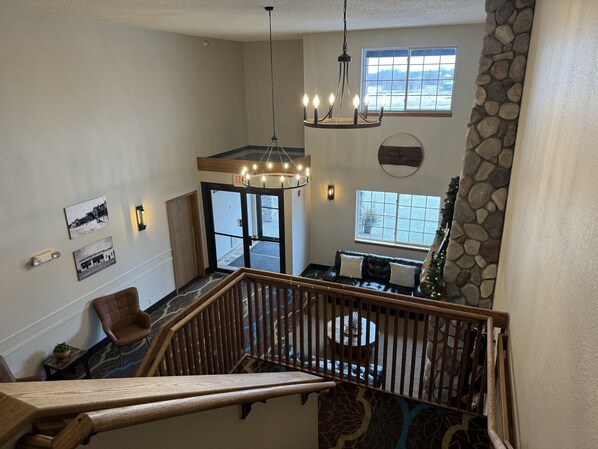 A spacious interior with a wooden staircase, a chandelier, and a stone accent wall.