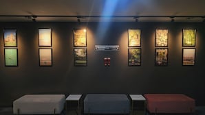 Un hall d’hôtel avec une rangée de lits, un panneau indicateur et des tableaux encadrés accrochés au mur.