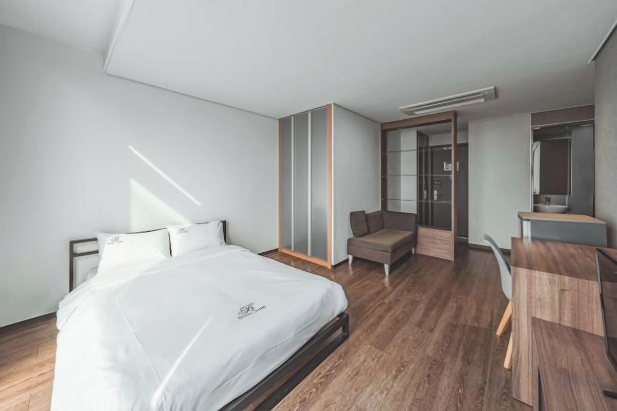 Una habitación de hotel moderna con cama, escritorio, silla y armario.