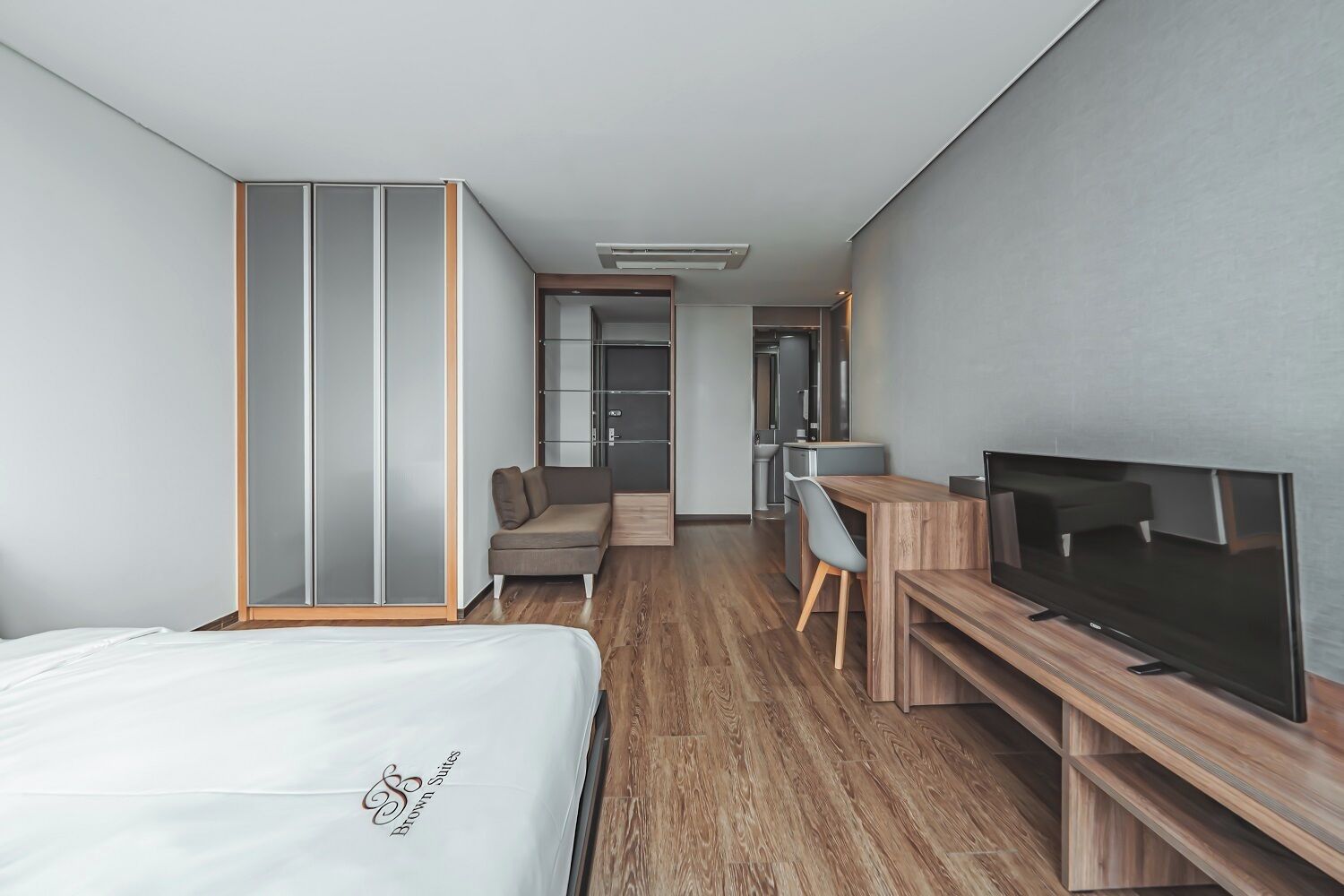 Una habitación de hotel con cama, escritorio con televisor, sofá y armario.