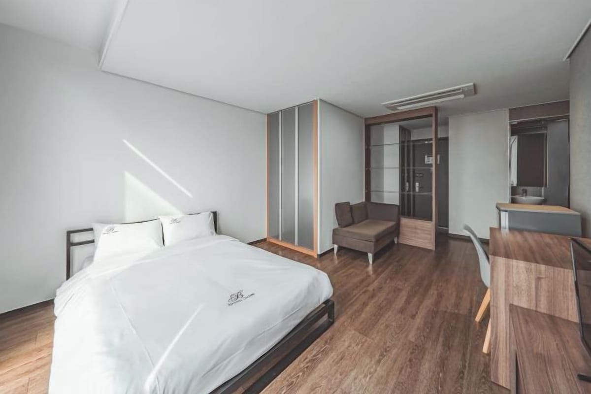 Ett modernt hotellrum med en stor säng, ett skrivbord, en stol och en garderob.