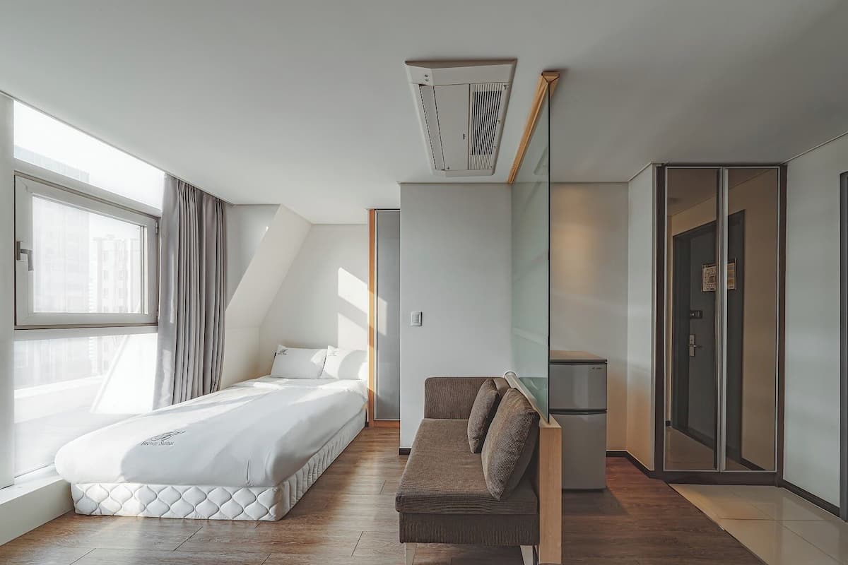 Ein modernes Hotelzimmer mit einem Bett, einer Couch, einem Kleiderschrank und einem Deckenventilator.