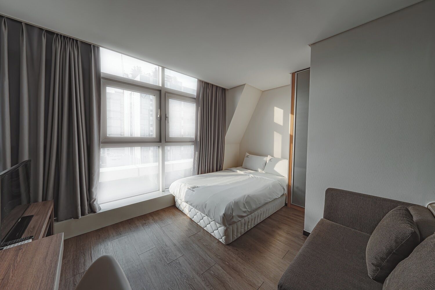 Ett modernt hotellrum med en säng, en soffa och ett skrivbord.