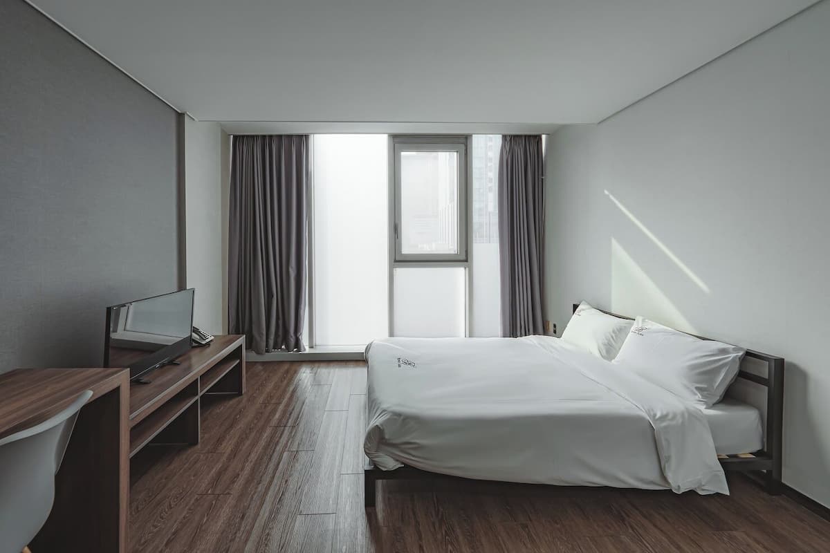 Ein modernes Hotelzimmer mit Bett, Schreibtisch und Fernseher.