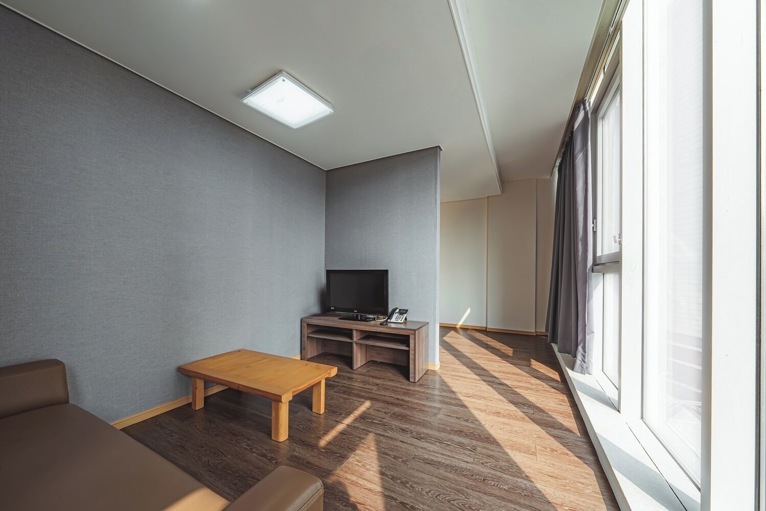 A modern living room with a flat-screen TV, a wooden coffee table, and a sofa.