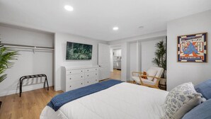 A modern bedroom with a large bed, a desk, and a chair. There is a painting on the wall and a poster on the wall. - Artful Heaven: Sleeps up to 6, Private Luxury ! (Pueblo)
