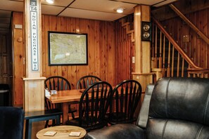 Un interior de madera con una mesa y sillas de comedor, un mapa en la pared y una escalera.