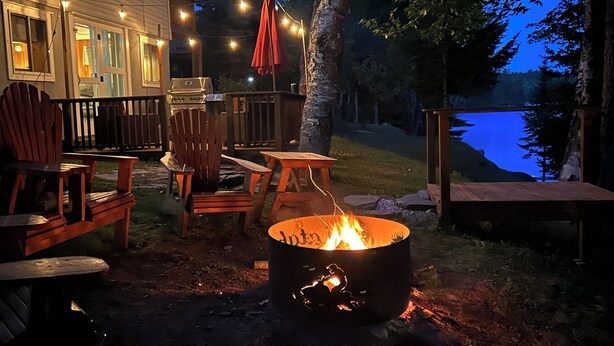 An outdoor patio with wooden chairs and a fire pit.