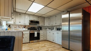A modern kitchen with white cabinets, stainless steel appliances, and a wooden floor.