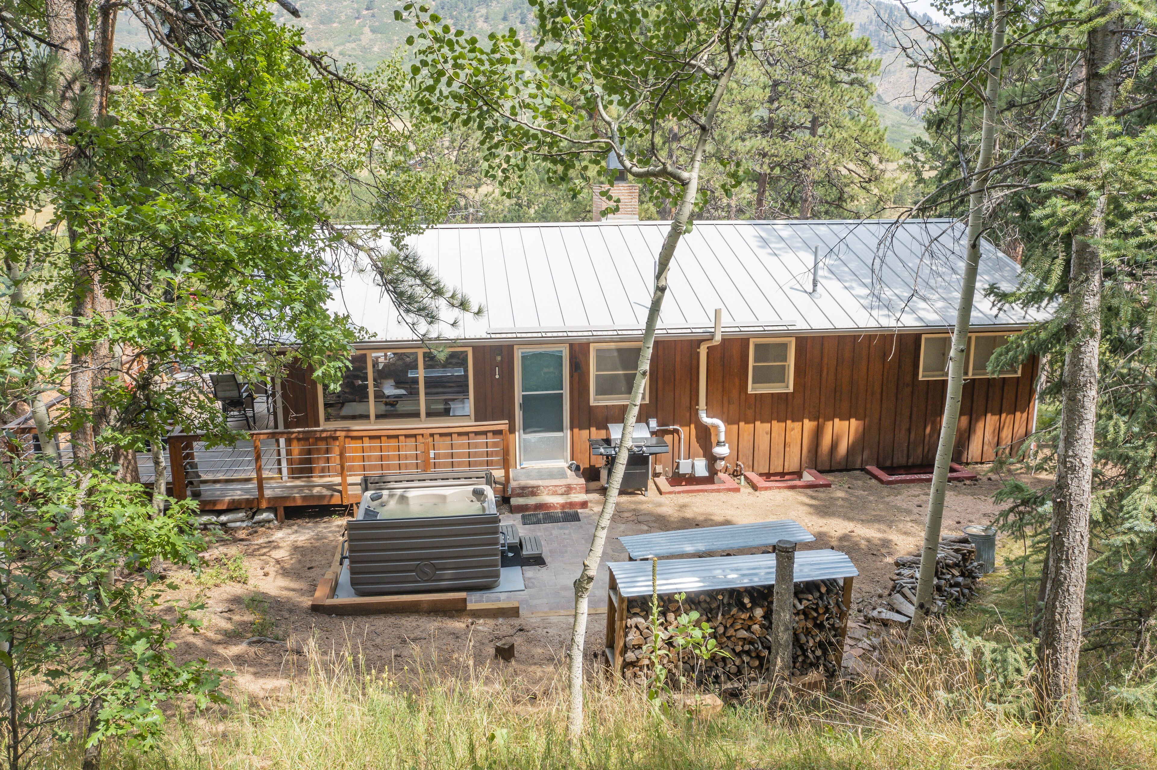 A rustic cabin with a metal roof, wooden exterior, and a deck area.