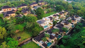 Vista aérea de una zona residencial con varias casas, una piscina y abundante vegetación.