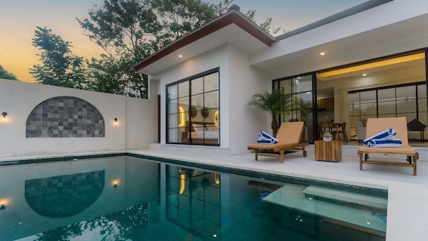 Una casa moderna con piscina, ventanas amplias y mobiliario exterior.