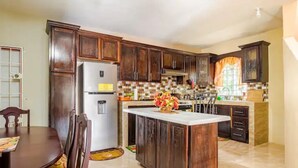 A kitchen with dark wooden cabinets, a white refrigerator, and a tiled backsplash.
