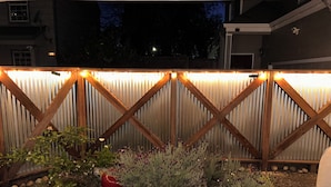 Ein Garten mit Holzzaun, Kies und verschiedenen Pflanzen.