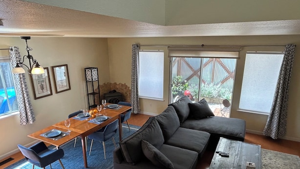 Ein Wohnzimmer mit einem Holzespeisetisch, gedeckt für vier Personen, einer schwarzen Couch und einem kleinen Couchtisch.