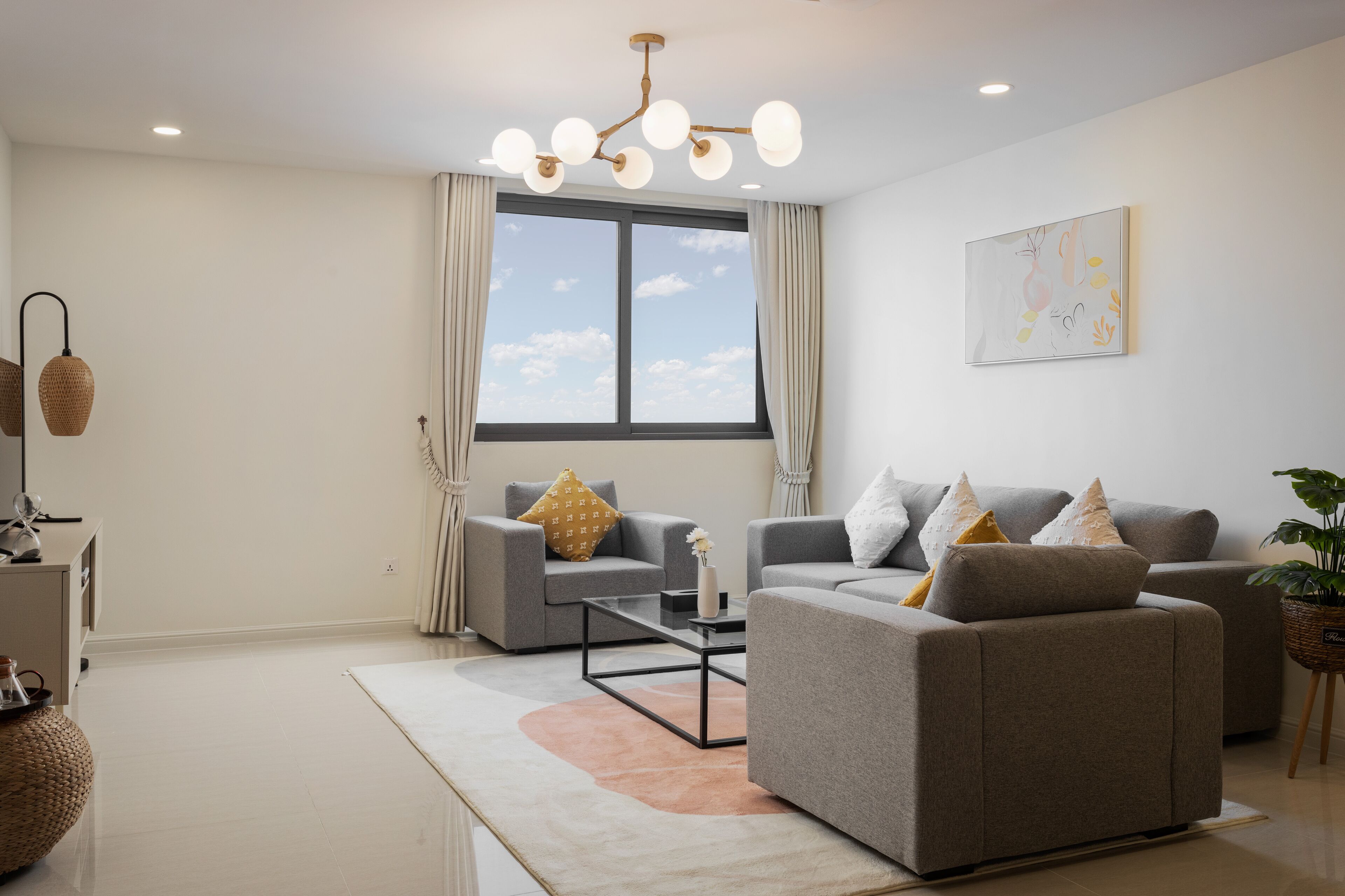 A modern living room with two grey sofas, a coffee table, and a large window with curtains.