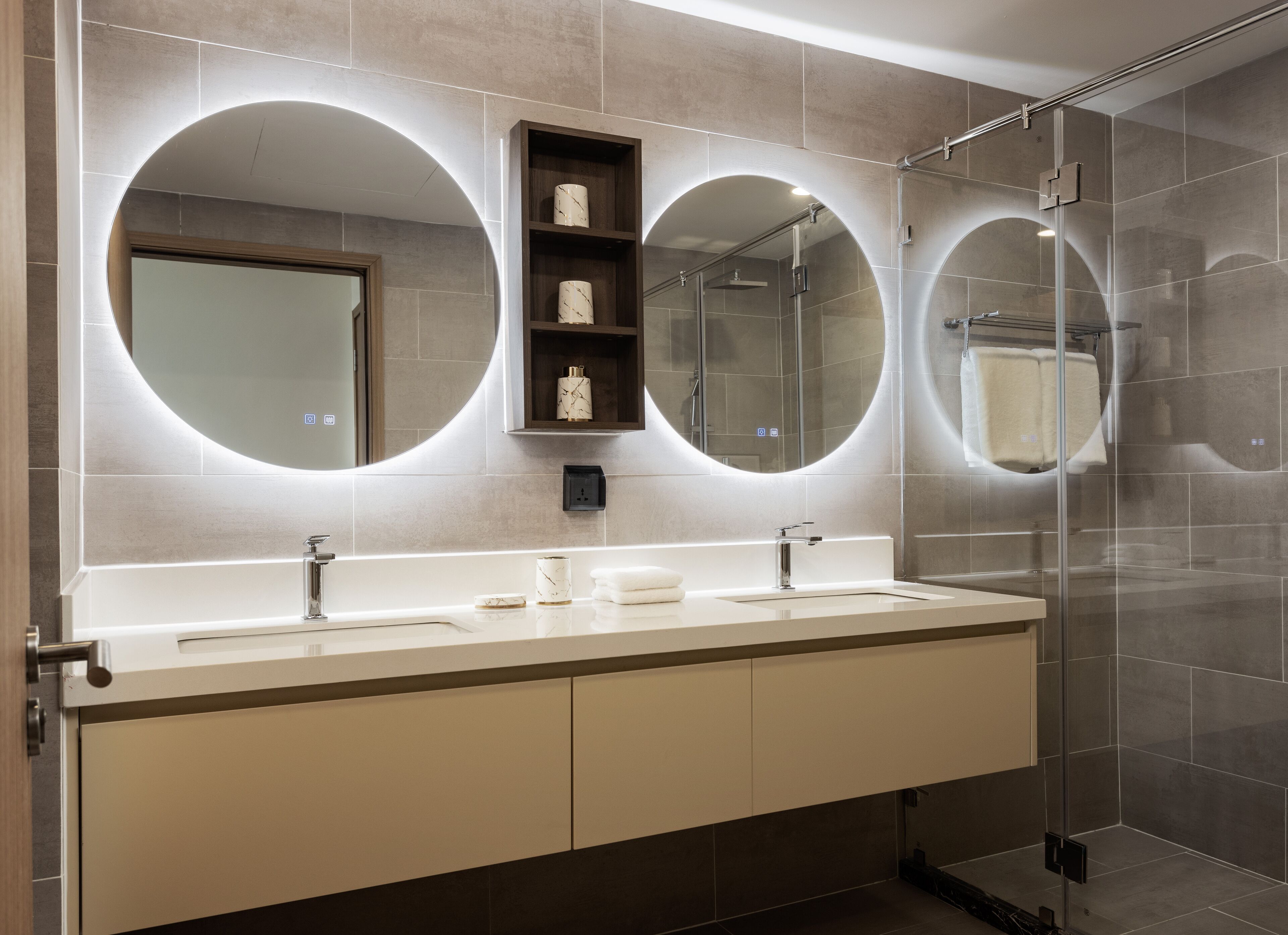 A modern bathroom with two sinks, a large mirror, and a glass shower enclosure.
