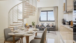 A modern living room with a curved staircase, a dining area, and a kitchen.