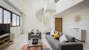 A modern living room with a spiral staircase, a sofa set, a coffee table, and a television.