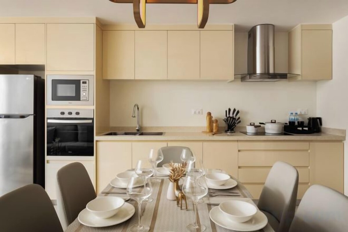 A modern kitchen with a built-in oven, microwave, and stainless steel range hood.